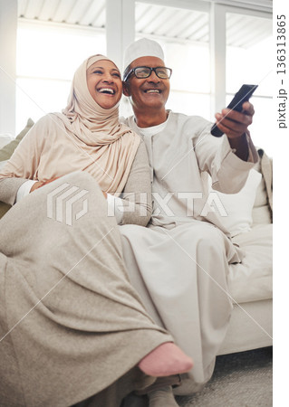 Relax, muslim and watching tv with old couple on sofa for streaming, movie and funny. Television, smile and happy with senior man and woman in living room at home for comedy, retirement and lounge Relax, muslim and watching tv with old couple on sofa for streaming, movie and funny. Television, smile and happy with senior man and woman in living room at home for comedy, retirement and lounge 136313865