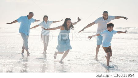 Travel, beach and happy family running together at the sea or ocean bonding for love, care and happiness. Summer, sun and parents with children or kids and grandparents on a holiday for freedom 136313954