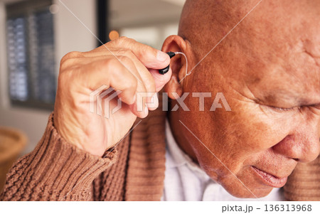 Hearing aid, ear and a senior man with a disability in his home closeup for listening to noise or volume. Healthcare, medical or deaf with a mature male person in his retirement house for wellness 136313968