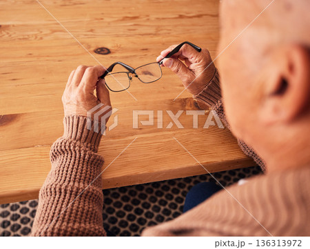 Senior man, hand holding glasses and eye care with vision, prescription lens and designer frame at table. Elderly guy, hands and spectacles for vision, eyesight and health at desk in retirement home 136313972
