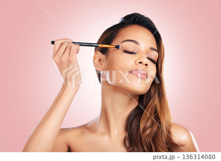 Makeup, eyeshadow and face of woman with brush on pink background for beauty, wellness and luxury. Cosmetology, aesthetic and female person with tools for foundation, cosmetics and glamour in studio Makeup, eyeshadow and face of woman with brush on pink background for beauty, wellness and luxury. Cosmetology, aesthetic and female person with tools for foundation, cosmetics and glamour in studio 136314080