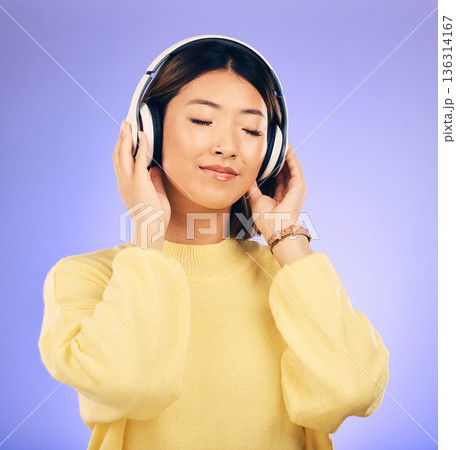 Headphones, music and happy Asian woman relax in studio for streaming app, subscription and radio. Calm, podcast and isolated female person listening to audio, song and track on purple background Headphones, music and happy Asian woman relax in studio for streaming app, subscription and radio. Calm, podcast and isolated female person listening to audio, song and track on purple background 136314167