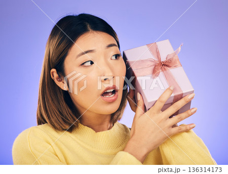 Thinking, gift and box with face of asian woman in studio for birthday, celebration and curious. Surprise, wow and party with female person and present on purple background for giveaway and package Thinking, gift and box with face of asian woman in studio for birthday, celebration and curious. Surprise, wow and party with female person and present on purple background for giveaway and package 136314173