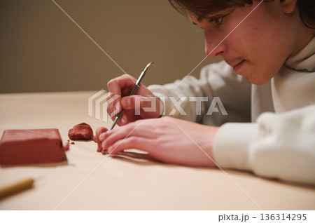 Young Artist Molding Clay at Home, Focused Hobby Session Creating Red Clay Forms 136314295