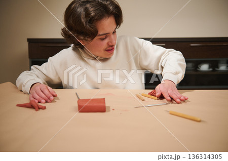 Young Boy Molding Clay At Table With Tools In A Hobby Studio Setting 136314305