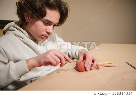 Young Man Molding Clay At Home With Tools, Focused Hobbyist Craft Project 136314314