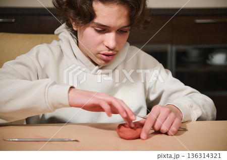 Young Boy Molding Clay At Home, Focused On Craft And Creative Clay Sculpture Project 136314321