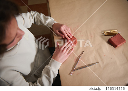 Young Boy Molding Clay At Home With Tools On A Brown Paper Table Young Boy Molding Clay At Home With Tools On A Brown Paper Table 136314326
