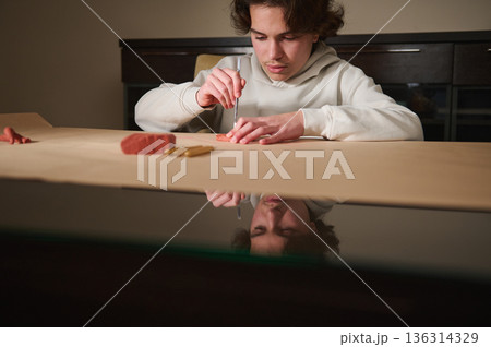 Young Boy Carving Clay at Home: Focused Hobbyist Sculpting with Tools on Craft Table 136314329