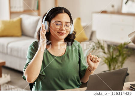 Laptop, music and streaming with a woman in her home, listening to the radio in the living room to relax. Computer, audio and headphones with a young female student in her house for education 136314429