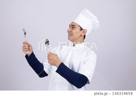 Young chef holding kitchen utensils and tasting food 136314659