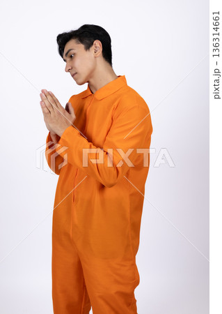 Male prisoner in orange jumpsuit with hands in prayer 136314661