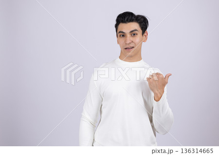 Man in white shirt pointing thumb sideways to copy space Man in white shirt pointing thumb sideways to copy space 136314665
