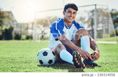 Man, soccer field and tie shoes for sports training, fitness games and performance on stadium ground. Portrait, athlete and happy football player prepare lace sneakers on grass pitch for competition 136314856