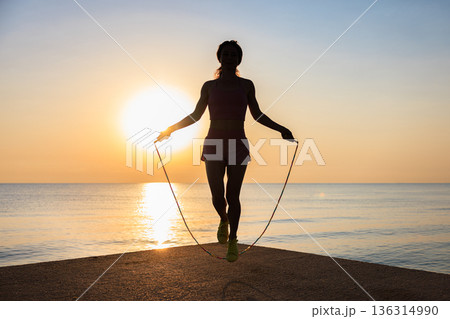 Fit woman jumping rope at the beach during summer vacation 136314990