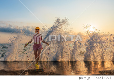 Fit woman jumping rope at the beach during summer vacation 136314991