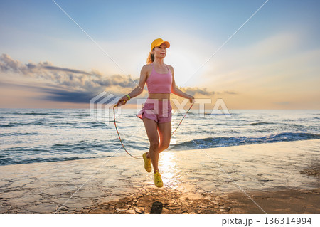 Fit woman jumping rope at the beach during summer vacation 136314994