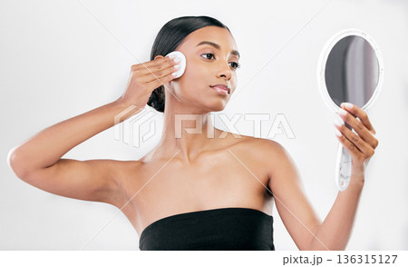 Woman, mirror and cotton pad for face, cosmetics and aesthetic skincare in studio on white background. Indian female model looking at reflection with beauty product for facial cleaning or dermatology Woman, mirror and cotton pad for face, cosmetics and aesthetic skincare in studio on white background. Indian female model looking at reflection with beauty product for facial cleaning or dermatology 136315127