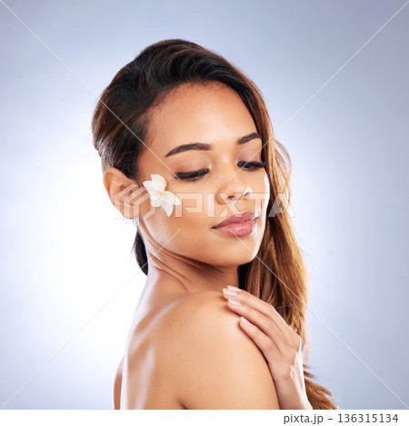 Beauty, skincare and woman with flower on face, natural makeup and spa treatment on white background. Dermatology, skin care glow and nature, model with floral and organic facial cosmetics in studio. Beauty, skincare and woman with flower on face, natural makeup and spa treatment on white background. Dermatology, skin care glow and nature, model with floral and organic facial cosmetics in studio. 136315134