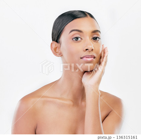 Beauty, hand on face and portrait a woman with natural skincare isolated on a white background. Dermatology, makeup glow and cosmetics with Indian female model for facial shine or self care in studio Beauty, hand on face and portrait a woman with natural skincare isolated on a white background. Dermatology, makeup glow and cosmetics with Indian female model for facial shine or self care in studio 136315161