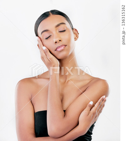 Hand on face, beauty and a woman with natural skin care isolated on a white background. Dermatology, makeup glow and cosmetics with Indian female model for facial shine and self love in studio Hand on face, beauty and a woman with natural skin care isolated on a white background. Dermatology, makeup glow and cosmetics with Indian female model for facial shine and self love in studio 136315162