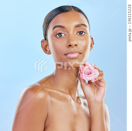 Woman, rose and natural beauty with cosmetics and eco friendly skincare on blue background. Flower, nature and sustainable dermatology with skin glow, female model and portrait in studio Woman, rose and natural beauty with cosmetics and eco friendly skincare on blue background. Flower, nature and sustainable dermatology with skin glow, female model and portrait in studio 136315228