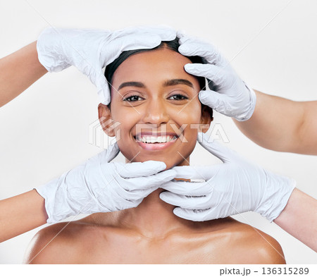 Woman, plastic surgery and gloves in studio portrait with smile for skin, inspection or change by white background. Girl, model and doctors hands for transformation, cosmetics and facial aesthetic 136315289