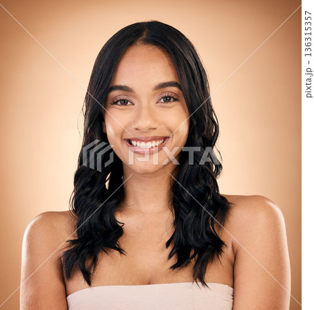 Portrait, hair and salon with a model woman in studio on a brown background for shampoo treatment. Smile, beauty and haircare with a happy young person looking confident about natural cosmetics 136315357