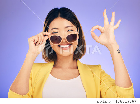 Happy asian woman, portrait and sunglasses, OK sign or fashion accessory against a purple studio background. Female person or model smile with okay gesture in satisfaction for perfect summer style Happy asian woman, portrait and sunglasses, OK sign or fashion accessory against a purple studio background. Female person or model smile with okay gesture in satisfaction for perfect summer style 136315367