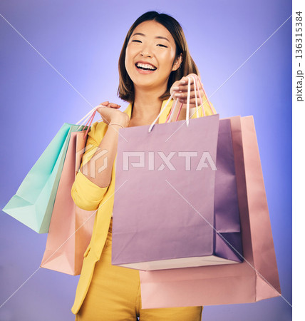Shopping bag, portrait and woman giving, offer or fashion discount, deal or sale on studio purple background. Giveaway, prize or competition of young customer, model or asian person winning in retail 136315384