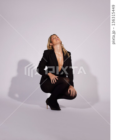 Fashion, suit and woman with confidence in studio isolated on a white background mockup space. Style, aesthetic and female model with formal clothes, classy makeup cosmetics and kneel with sexy pose 136315449
