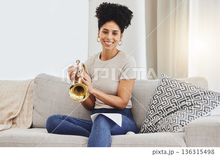 Portrait, woman and trumpet in home for music, learning and practice classic jazz song. Happy young female person, musician and brass horn instrument on sofa, living room and hobby of musical talent Portrait, woman and trumpet in home for music, learning and practice classic jazz song. Happy young female person, musician and brass horn instrument on sofa, living room and hobby of musical talent 136315498