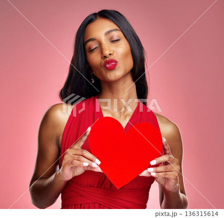 Woman, paper heart and kiss in studio with lips, makeup and beauty with romantic sign by red background. Girl, fashion model and cardboard emoji with love for cosmetic, valentines day date or pout Woman, paper heart and kiss in studio with lips, makeup and beauty with romantic sign by red background. Girl, fashion model and cardboard emoji with love for cosmetic, valentines day date or pout 136315614