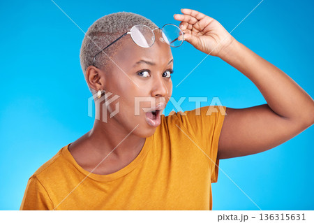 Portrait, news and black woman shocked, gossip and announcement against a blue studio background. Face, female person and model with glasses, surprise and deal with omg facial and wow with expression Portrait, news and black woman shocked, gossip and announcement against a blue studio background. Face, female person and model with glasses, surprise and deal with omg facial and wow with expression 136315631