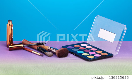 Makeup, product and palette for color in studio, brush and cosmetics for beauty, mock up and blue background. Powder, mascara and skincare with transformation, change and eyeshadow for aesthetic 136315636