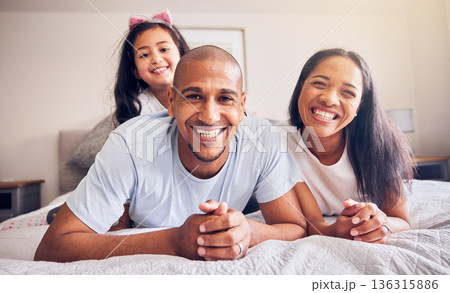 Portrait, happy and a family relax on a bed at home while laughing and playing for quality time. Man, woman or hispanic parents and kid together in the bedroom for morning bonding with love and care 136315886