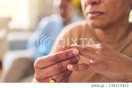 Senior couple, hands and ring in divorce, fight or conflict from disagreement or argument on sofa at home. Elderly man and woman in depression, infertility or cheating and toxic marriage in the house 136315923