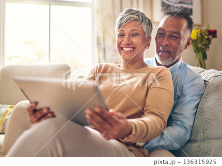 Happy, streaming and a couple with a tablet on the sofa for communication, social media or online chat. Smile, house and a senior man and woman with a movie on technology on the couch and laughing 136315925