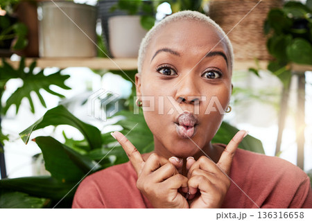 Black woman, silly face and home with comedy feeling happy with plants. African female person, portrait and crazy with hand sign and funny pout with comic confidence and house greenery with joke 136316658