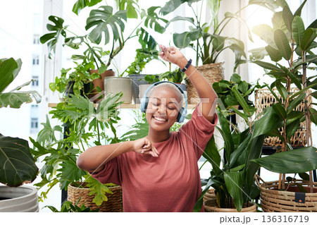Music, dance and headphones with a black woman in her home by plants while streaming an audio playlist. Freedom, radio and subscription service with a happy young female person eyes closed in a house Music, dance and headphones with a black woman in her home by plants while streaming an audio playlist. Freedom, radio and subscription service with a happy young female person eyes closed in a house 136316719