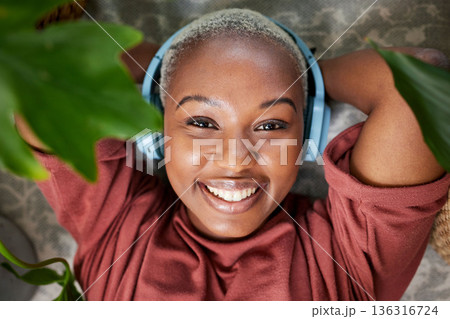 Woman, portrait and headphones for listening to music to relax with plants for peace and calm. Face of a happy black female person streaming sound, audio and podcast or radio online at home Woman, portrait and headphones for listening to music to relax with plants for peace and calm. Face of a happy black female person streaming sound, audio and podcast or radio online at home 136316724