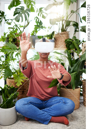 Hands, virtual reality and headset of a woman at home for metaverse, 3d world or interaction. Black person with plants and vr glasses for ecology, ai or touch for video game or online experience Hands, virtual reality and headset of a woman at home for metaverse, 3d world or interaction. Black person with plants and vr glasses for ecology, ai or touch for video game or online experience 136316726