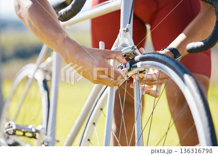 Bicycle, wheel and a man outdoor fixing puncture or problem while cycling. Bike, hands and a sports person, cyclist or athlete check air for maintenance, safety or repair on broken or flat tyre 136316798