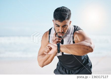 Man, fitness and checking watch for pulse, heart rate or performance on break after workout on the beach. Fit, active and sporty male person with wristwatch for monitoring body exercise by the ocean Man, fitness and checking watch for pulse, heart rate or performance on break after workout on the beach. Fit, active and sporty male person with wristwatch for monitoring body exercise by the ocean 136317127