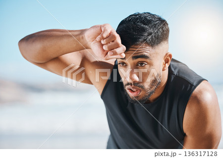 Tired, sweating and fitness break for man outdoor after training, running or cardio workout on blurred background. Sweat, face and Indian male runner with sports fatigue, dehydration from exercise 136317128