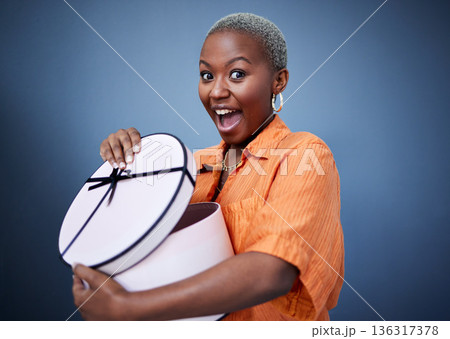 African woman, open present or box in studio portrait with excited smile, surprise and blue background. Girl, happy and wow with package, gift and fashion for celebration, winner and birthday party 136317378