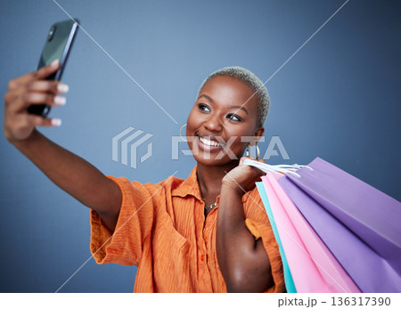 Selfie, happy and woman with shopping bags in studio after sale, promotion or discount. Smile, excited and African female person or customer taking picture after buying products by gray background. Selfie, happy and woman with shopping bags in studio after sale, promotion or discount. Smile, excited and African female person or customer taking picture after buying products by gray background. 136317390