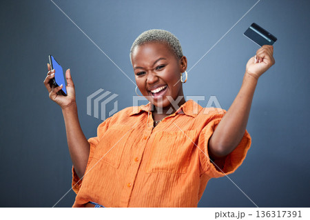 Winner, phone and credit card with a black woman online shopping in studio on a gray background. Mobile, ecommerce and wow with a happy young female shopper in celebration of deal or sale success Winner, phone and credit card with a black woman online shopping in studio on a gray background. Mobile, ecommerce and wow with a happy young female shopper in celebration of deal or sale success 136317391