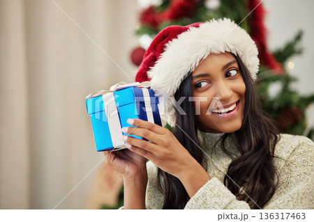 Christmas, curious or happy woman with a gift or box in present on a holiday celebration at home. Guessing, smile or excited Indian girl with present with giveaway prize package in a house in winter Christmas, curious or happy woman with a gift or box in present on a holiday celebration at home. Guessing, smile or excited Indian girl with present with giveaway prize package in a house in winter 136317463