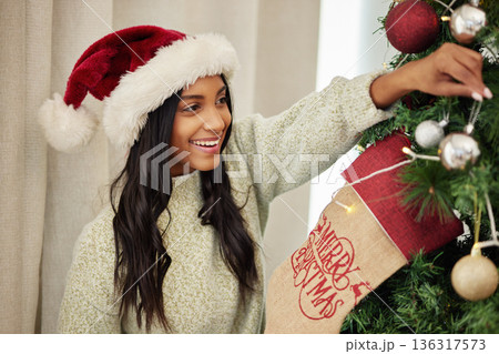 Christmas, decoration or excited girl with tree in home for fun holiday or vacation break with smile. Relax, happy or Indian woman hanging ornaments or decorations for festive celebration in house 136317573